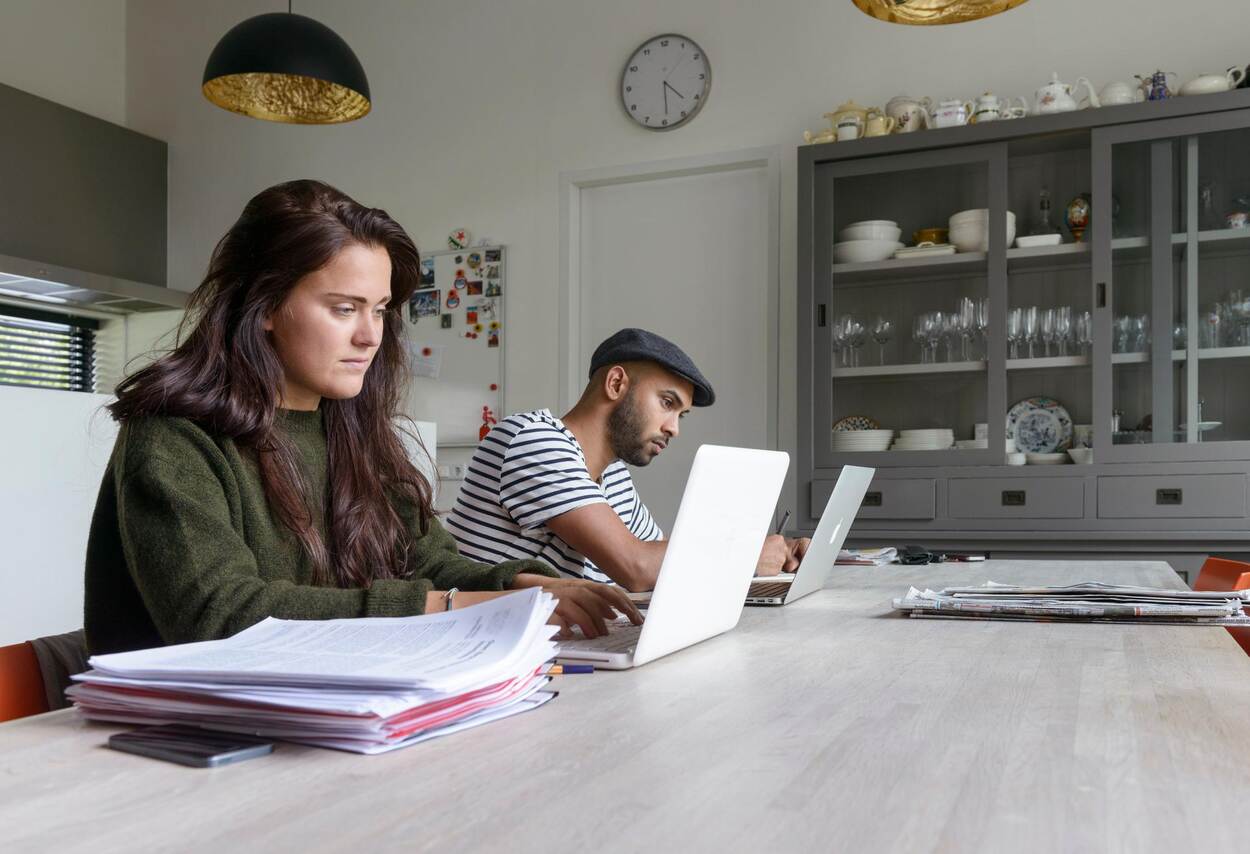 Vrouw en man zitten met laptop aan de keukentafel